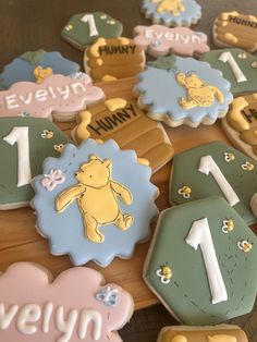 winnie the pooh cookies are arranged on a wooden table with name tags and numbers