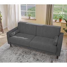 a gray couch sitting on top of a rug next to a window