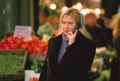 a woman is talking on her cell phone while shopping at an outdoor farmers'market