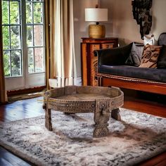 a living room with a couch, coffee table and rug in front of a window