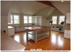 an empty kitchen with wooden floors and white cabinets in the corner, along with large windows