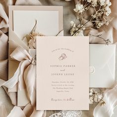 the wedding stationery is laid out on top of some satin fabric and has flowers in it