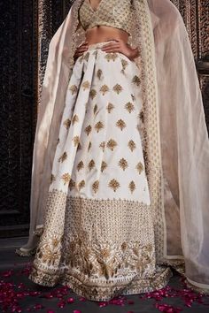 Ivory silk lehenga with an attached cancan and gold floral embroidery. Comes with a padded blouse and a dupatta.
Components: 3
Pattern: Embroidered
Type Of Work: Floral
Neckline: Deep V Neck
Sleeve Type: Sleeveless
Fabric: Silk
Color: Ivory
Other Details: 
Attached lining
Product Weight: 2 Kgs
Occasion: Wedding - Aza Fashions White Silk Anarkali Set For Navratri, White Chanderi Sharara For Reception, Off White Floor-length Sharara With Zari Work, White Silk Set For Reception, White Silk Sets For Reception, White Silk Set With Gota Work, White Chanderi Dress With Gota Work, White Dola Silk Sharara For Wedding, White Silk Sharara For Reception