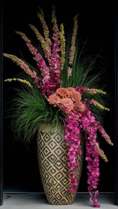 a vase filled with lots of flowers on top of a table next to a wall