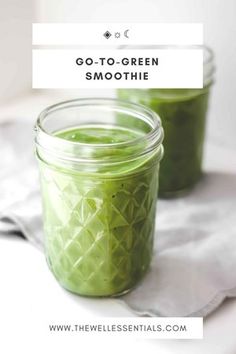 two jars filled with green smoothie sitting on top of a white cloth next to each other