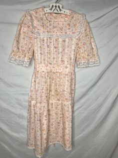 Darling vintage JC Penney's girls dress in a pink floral print . It has its original Union Made USA Tag attached. Tagged size 10, with a wide ruffle at the bottom. Everything is trimmed in white lace. Tag Size:  10 Chest, underarm to underarm: 15" Length:  31" Shoulder to shoulder 11" Condition: Clean, bright, few signs of use. Tag is crispy. 65% poly/35% cotton Pink Fitted Cottagecore Dress, Short Sleeve Prairie Dress With Ruffles For Garden Party, Vintage Short Sleeve Ruffled Dress For Spring, Vintage Short Sleeve Dress With Ruffles For Spring, Spring Prairie Dress With Ruffles And Short Sleeves, Feminine Spring Prairie Dress With Short Sleeves, Feminine Short Sleeve Prairie Dress For Spring, Spring Victorian Dress With Ruffles For Garden Party, Fitted Pink Vintage Cottagecore Dress