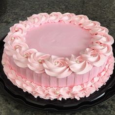 a pink frosted cake sitting on top of a black plate