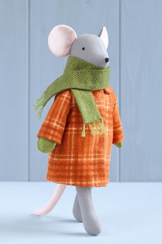 a stuffed mouse wearing an orange coat and green scarf