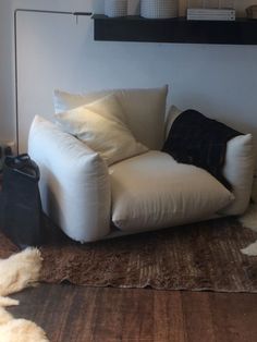 a white chair sitting on top of a wooden floor next to a wall mounted shelf