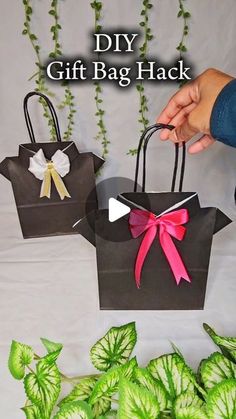 two bags with bows on them are sitting next to some green plants and ivys