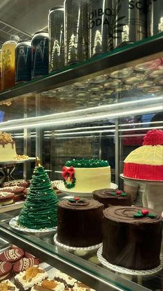 many cakes and pastries are on display in a bakery case with glass shelves filled with frosting