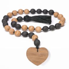 a wooden heart and black bead necklace with a tassel hanging from the front