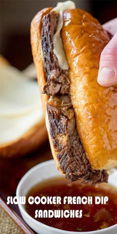 a hand is holding a sandwich over a bowl of soup with the words slow cooker french dip sandwiches