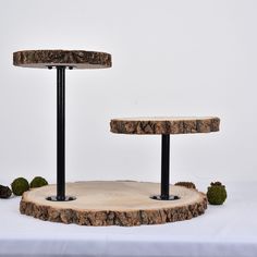 three tiered wooden table with black metal legs and wood slices on the bottom, in front of white backdrop