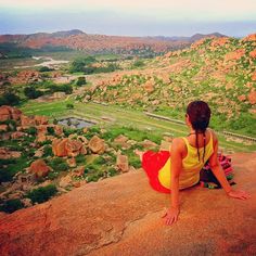 a woman sitting on top of a rock next to a valley