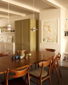 a dining room table with four chairs and a painting on the wall in the background