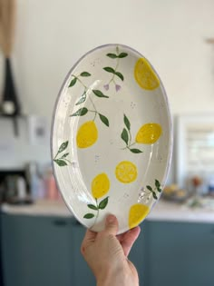 a person holding up a glass plate with lemons on it in a kitchen area