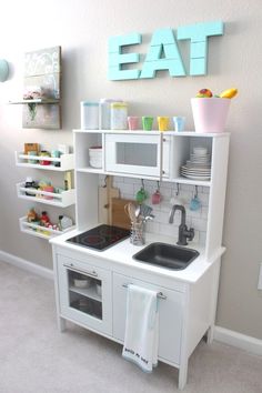 a play kitchen with white cabinets and black sink