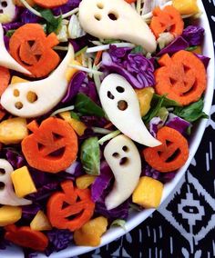 a white bowl filled with vegetables and carved faces