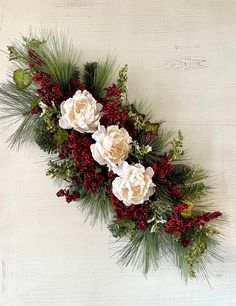 flowers and greenery are arranged on a white background with red berries, pine cones and evergreens