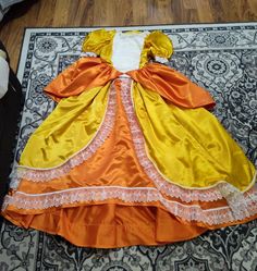 an orange and yellow dress laying on top of a rug