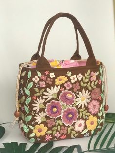 a brown purse with flowers and leaves on it