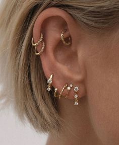 a close up of a person with ear piercings on their ears and wearing gold jewelry