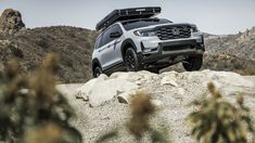 the front end of a silver honda passport parked on top of a rock in the desert