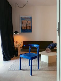 a blue chair sitting next to a white table in a living room under a painting