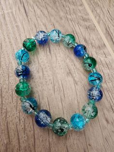 Who doesn't love a pop of color? And that's exactly what you'll get with this brightly colored bracelet featuring 10mm round glass beads in blue, green and aqua with black splatters and translucent aqua seed beads. Bracelet is approximately 7.5 to 8 inches and is made with clear stretchy elastic and should fit most wrists. If you need a smaller or larger size, message me and I'll see what I can do! All bracelets are sold AS IS. You will receive the one shown in the picture. Please be careful with the bracelet as it is not indestructible. Avoid water, gels, lotions, soaps, etc. Not intended for children. Please note that beads are a choking hazard and I am not liable if they are ingested. Turquoise Glass Round Beads Bracelets, Blue Glass Stretch Bracelet With Round Beads, Adjustable Turquoise Glass Bracelets, Turquoise Stretch Bracelet With Colorful Beads, Glass Beaded Bracelets With Spacer Beads, Hypoallergenic Green Beaded Round Bracelets, Green Hypoallergenic Beaded Bracelets, Hypoallergenic Green Beaded Bracelets, Green Glass Beaded Bracelets With Round Beads