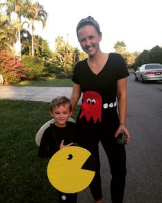 a woman standing next to a little boy holding a paper pacman