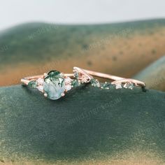 two rings with green and white stones on top of each other, sitting on a rock