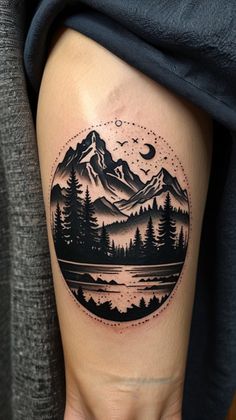 a woman's leg with a mountain scene tattoo on the side of her thigh