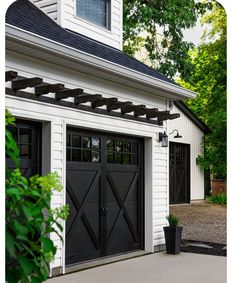 a white house with two black garage doors