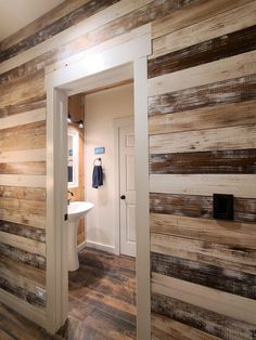 an open door leading to a bathroom with wood planks on the walls and floor