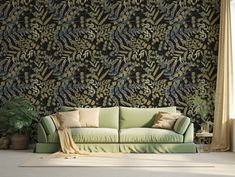 a green couch sitting in front of a black wallpapered with leaves and plants