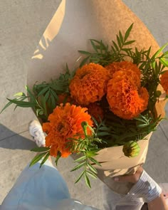 a person holding a bouquet of orange flowers