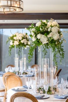 there are many tall vases with flowers on top of the tables at this wedding reception