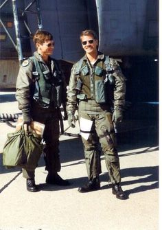 two men standing next to each other in front of an airplane