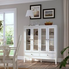 a white china cabinet with glass doors in a dining room