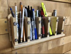 several pens, pencils and markers are in a holder on a wooden cabinet door