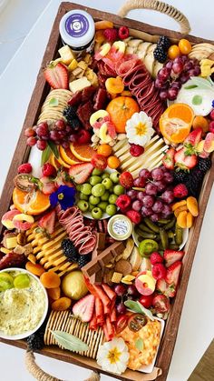 a tray filled with assorted fruits and cheeses on top of a white table