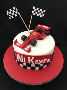 a red and white cake with a racing car on the top that says ali kayra