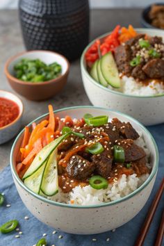 two bowls filled with rice, beef and veggies next to chopsticks