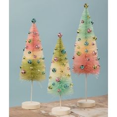 three small christmas trees with ornaments on them