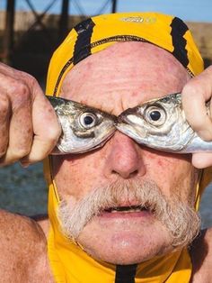 an older man holding up two fish in front of his eyes