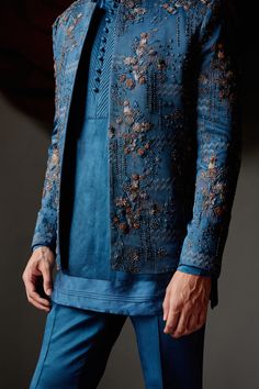 New Teal Short Jacket | Jatin Malik Introducing our latest creation: the teal short jacket, showcasing a new shade of elegance. Adorned with intricate linear floral hand embroidery, this jacket exudes sophistication and style. Highlighted with antique moti, dabka, and shades of brown, it captures attention with its intricate detailing and refined craftsmanship. Paired effortlessly with a tone-on-tone short-length kurta and tapered trousers, this ensemble offers a contemporary yet timeless look, perfect for any occasion. Whether it's a formal event or a stylish gathering, this outfit is sure to make a statement with its unique color palette and exquisite design. Included in purchase: Short Jacket, Kurta, Trousers Product Specification Color: Teal blue Fabric: Linen Silk Occasion: Engagement Bridegroom Outfits, Sf Fashion, Jodhpuri Suits, Floral Hand Embroidery, Indian Groom Wear, Sangeet Outfit, Gents Kurta, Mens Kurta Designs