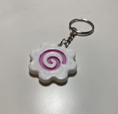 a pink and white swirl keychain sitting on top of a table