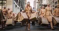 a group of people walking down a street with bags on their backs and horses pulling them