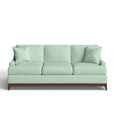 a light green couch with two pillows on the back and one pillow on the side